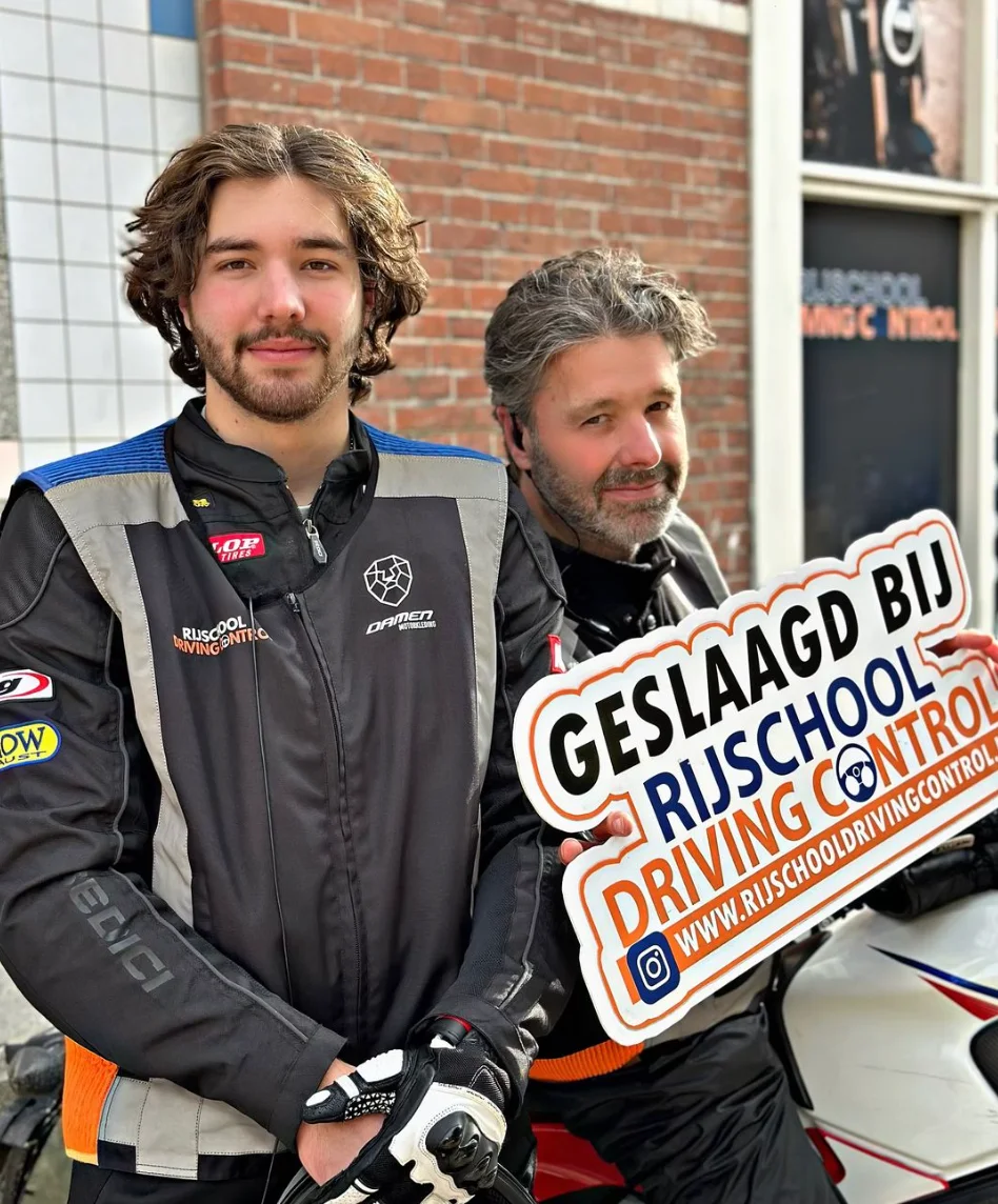 Twee geslaagde motorleerlingen met Geslaagd-bord bij Rijschool Driving Control Rotterdam